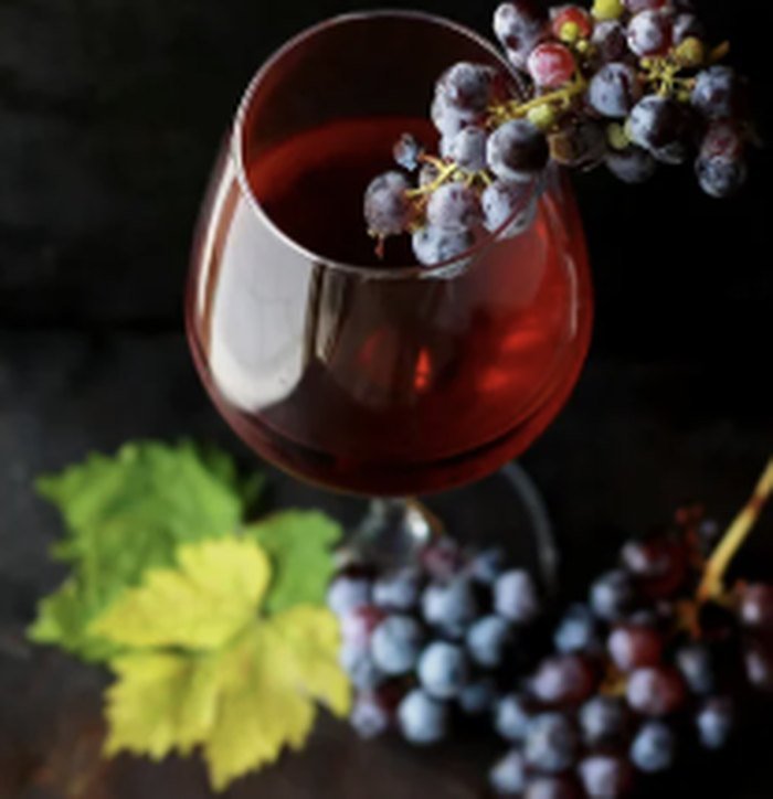 Verre de vin rouge et grappes de raisin dans une lumière sombre